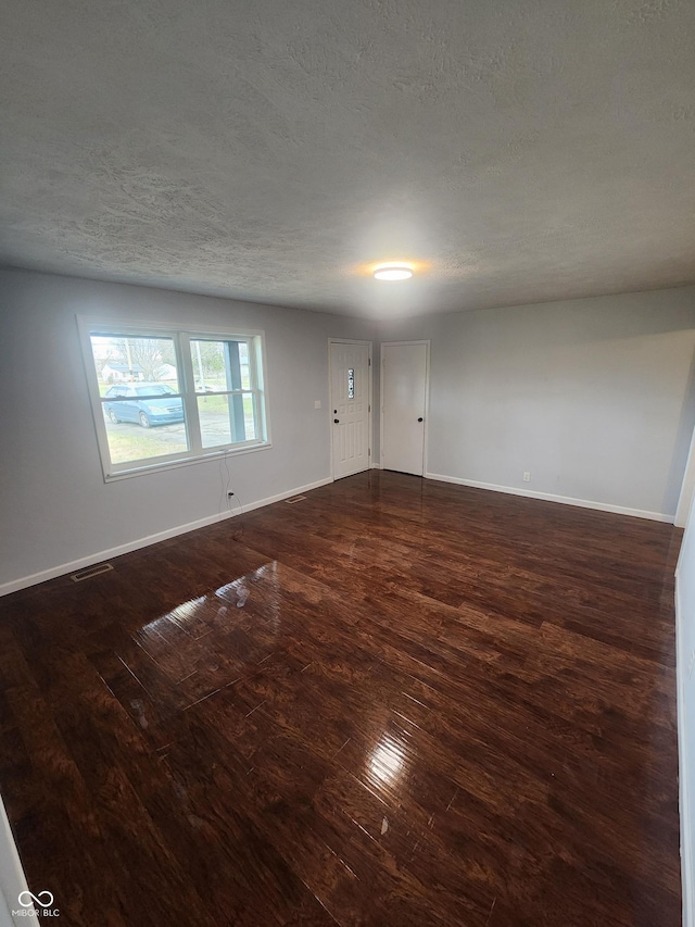 empty room with a textured ceiling and dark wood-type flooring