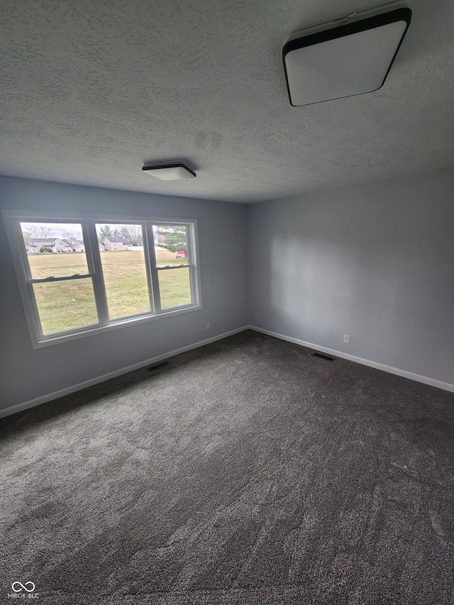 unfurnished room featuring dark carpet and a textured ceiling