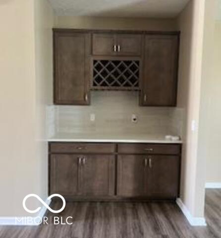 bar with dark brown cabinets and dark wood-type flooring