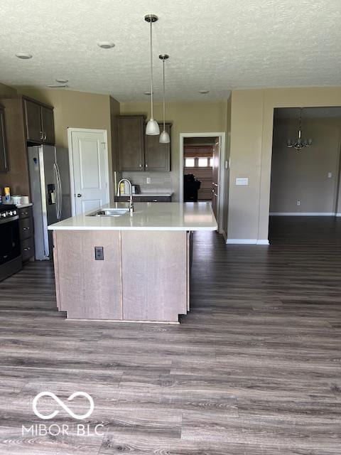 kitchen with dark brown cabinets, sink, dark wood-type flooring, and a center island with sink