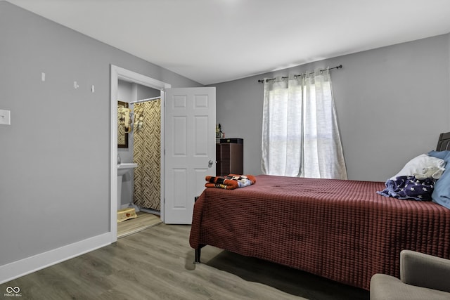 bedroom featuring connected bathroom, hardwood / wood-style floors, and sink