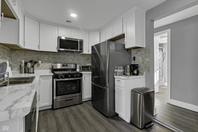 kitchen featuring white cabinetry, sink, stainless steel appliances, dark wood-type flooring, and decorative backsplash