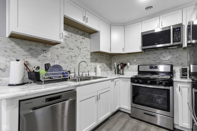 kitchen featuring white cabinets, decorative backsplash, stainless steel appliances, and sink