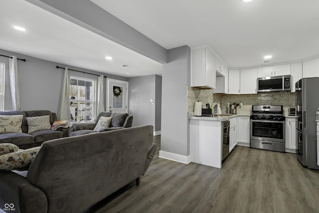 kitchen featuring white cabinets, stainless steel appliances, hardwood / wood-style flooring, and tasteful backsplash