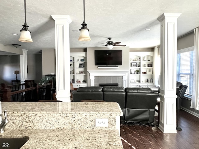 living room with sink, built in shelves, ceiling fan, ornate columns, and a textured ceiling