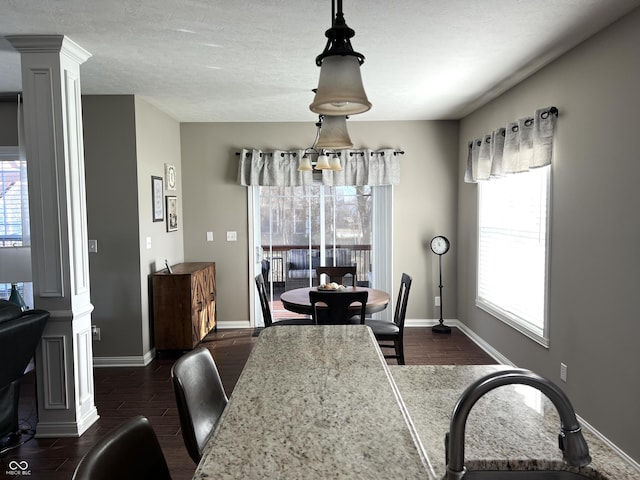 dining area featuring ornate columns, dark hardwood / wood-style flooring, and sink