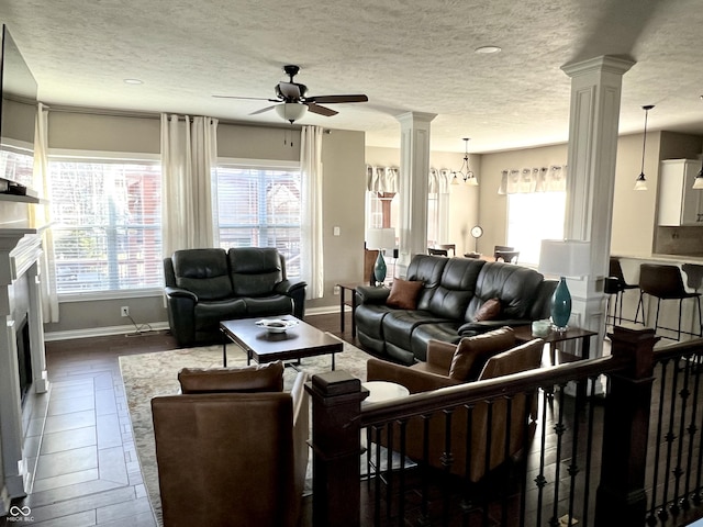 living room featuring ceiling fan with notable chandelier, a healthy amount of sunlight, a textured ceiling, and dark wood-type flooring