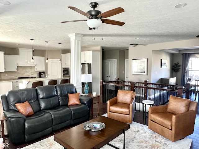 living room featuring ornate columns, ceiling fan, a textured ceiling, and hardwood / wood-style flooring