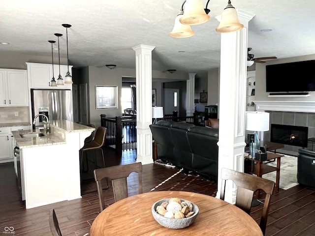 dining room with a tile fireplace, ceiling fan, sink, and a textured ceiling