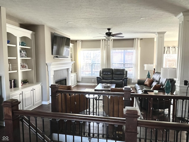 living room featuring ceiling fan, wood-type flooring, and a textured ceiling