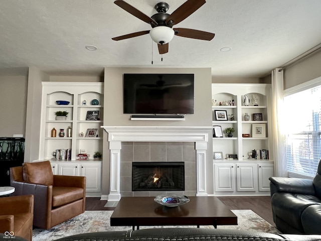 living room featuring a fireplace, dark hardwood / wood-style floors, a wealth of natural light, and ceiling fan