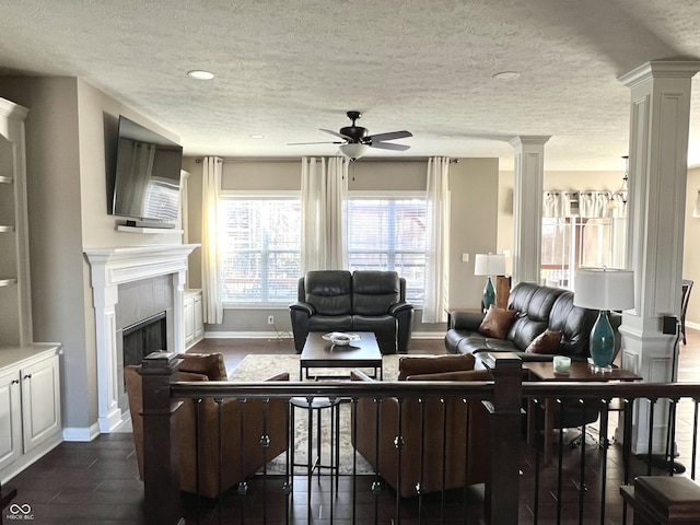 living room with ceiling fan, dark hardwood / wood-style flooring, a textured ceiling, and a tiled fireplace