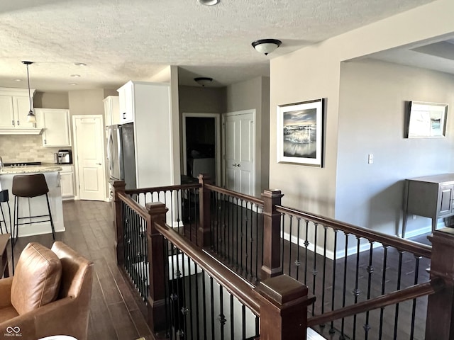 hall featuring dark wood-type flooring and a textured ceiling