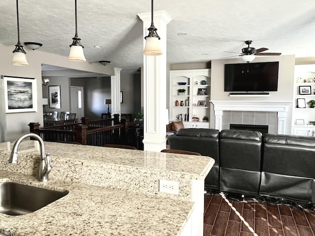 kitchen featuring light stone countertops, a textured ceiling, decorative light fixtures, and sink