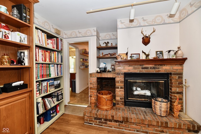 sitting room with wood-type flooring and a brick fireplace