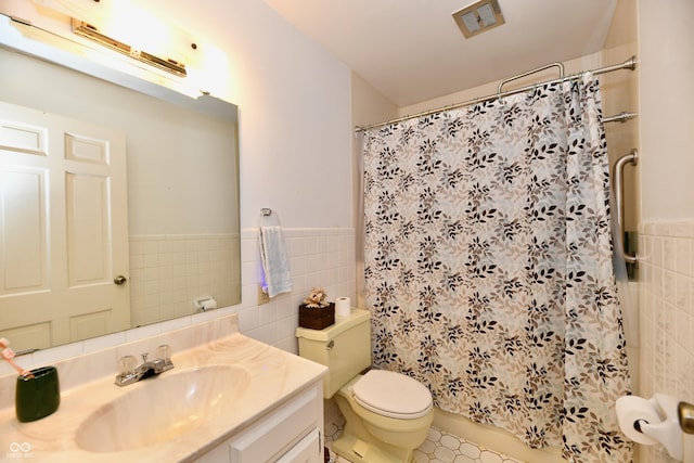 bathroom with walk in shower, vanity, toilet, and tile walls