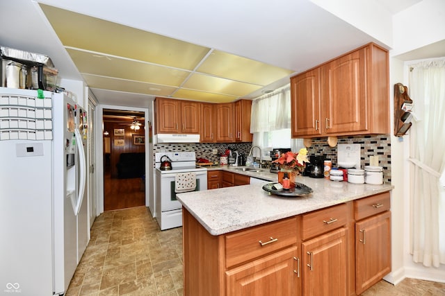 kitchen with backsplash, light stone countertops, sink, and white appliances