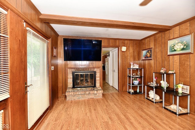 living room with beam ceiling, wood walls, a fireplace, and light hardwood / wood-style flooring