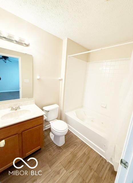 full bathroom with wood-type flooring, a textured ceiling,  shower combination, toilet, and vanity