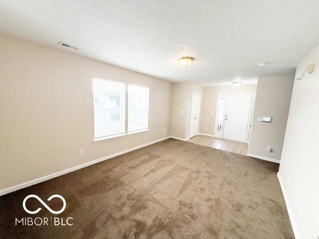 unfurnished room featuring a textured ceiling and carpet floors