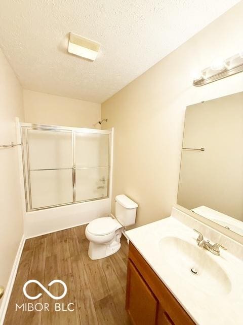 full bathroom with vanity, a textured ceiling, wood-type flooring, enclosed tub / shower combo, and toilet