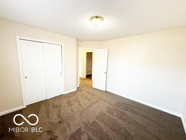 unfurnished bedroom featuring dark colored carpet, a textured ceiling, and a closet