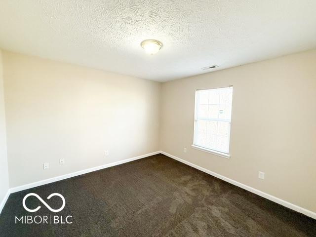 carpeted empty room with a textured ceiling