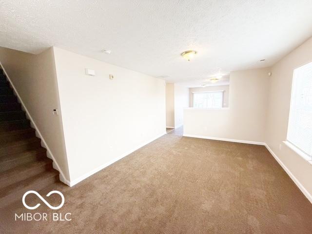 carpeted empty room with a textured ceiling