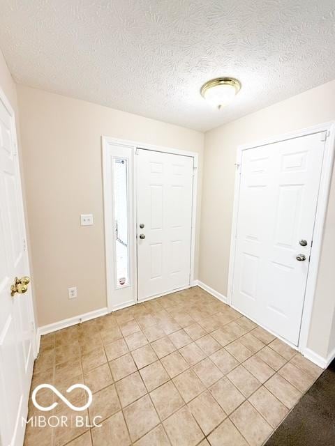 entrance foyer with a textured ceiling and light tile patterned flooring