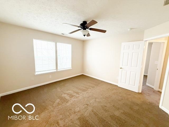 carpeted spare room with ceiling fan and a textured ceiling