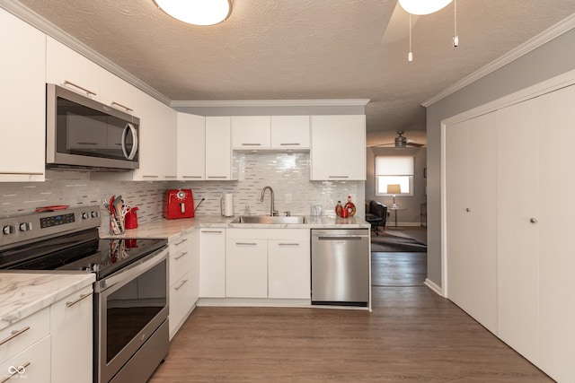 kitchen with appliances with stainless steel finishes, a textured ceiling, white cabinetry, and sink