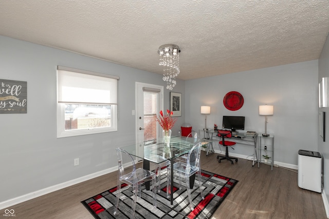 dining area featuring dark hardwood / wood-style flooring, a textured ceiling, and an inviting chandelier