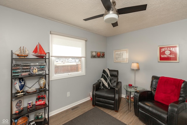 living area featuring hardwood / wood-style floors, a textured ceiling, and ceiling fan