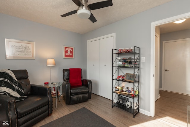 sitting room with ceiling fan, a textured ceiling, and light wood-type flooring