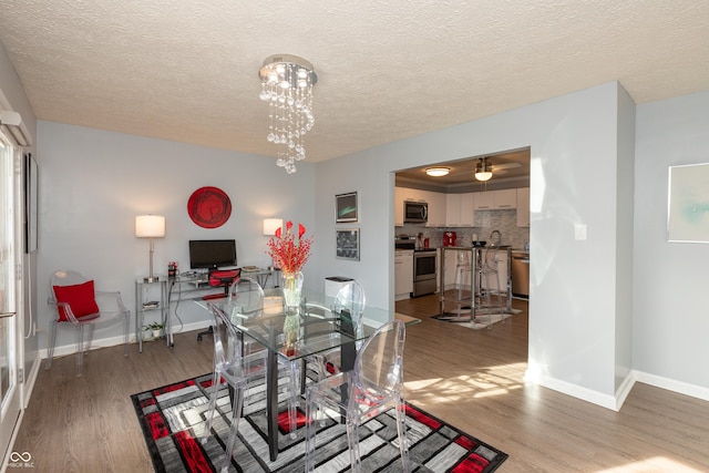 dining space featuring hardwood / wood-style floors, a notable chandelier, and a textured ceiling