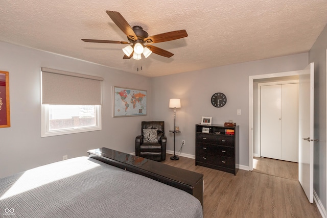 bedroom featuring ceiling fan, light hardwood / wood-style floors, and a textured ceiling