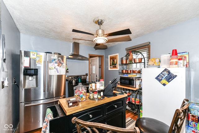 kitchen featuring ceiling fan, wall chimney exhaust hood, stainless steel appliances, a textured ceiling, and hardwood / wood-style flooring