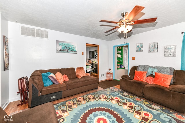 living room with wood-type flooring, a textured ceiling, and ceiling fan