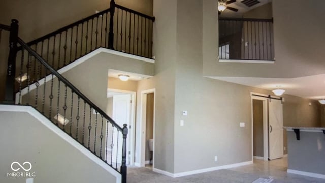 stairs with a towering ceiling, a barn door, and ceiling fan