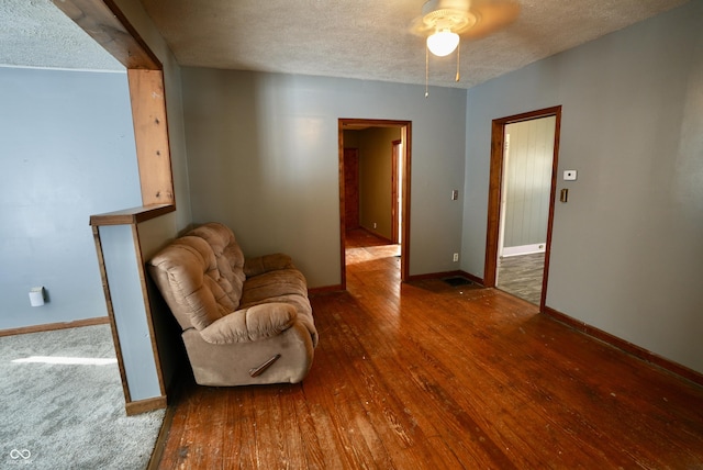 living area featuring ceiling fan, a textured ceiling, and wood-type flooring