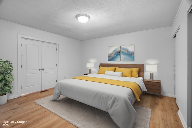 bedroom with a textured ceiling, light hardwood / wood-style flooring, and a closet