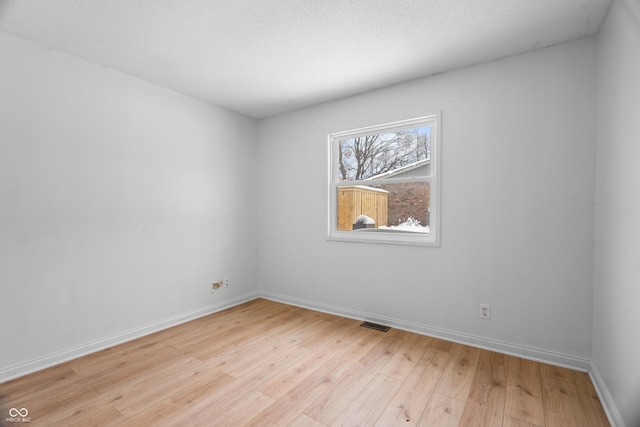 empty room with a textured ceiling and light wood-type flooring