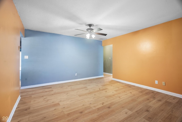 empty room featuring ceiling fan, light wood-type flooring, and a textured ceiling