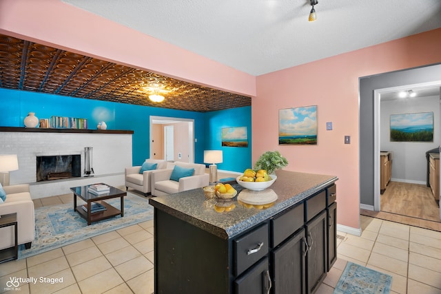 kitchen with a fireplace, a textured ceiling, a center island, and light tile patterned flooring