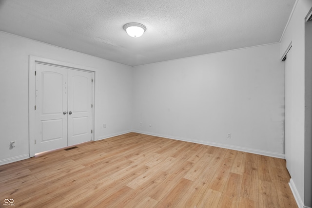 unfurnished bedroom with a closet, a textured ceiling, and light hardwood / wood-style flooring