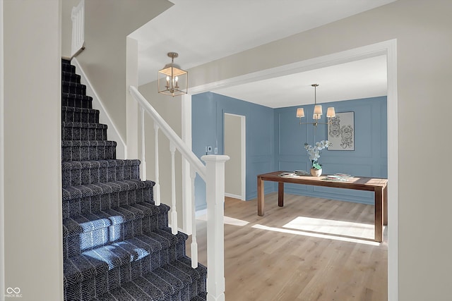 stairway with hardwood / wood-style floors and a notable chandelier