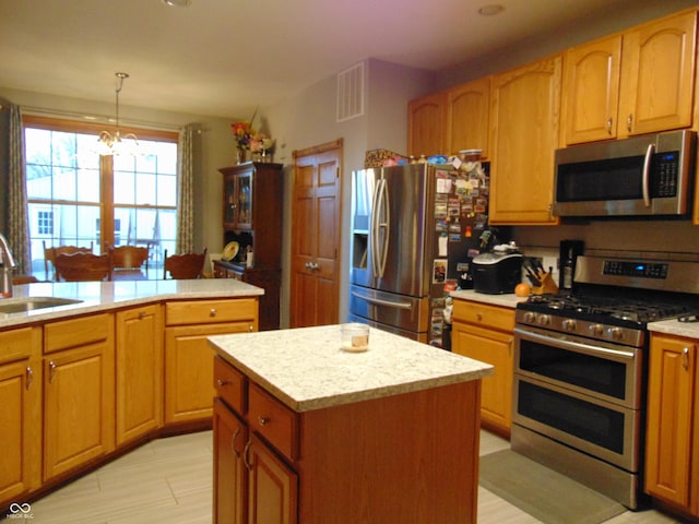 kitchen featuring a center island, hanging light fixtures, sink, appliances with stainless steel finishes, and a notable chandelier