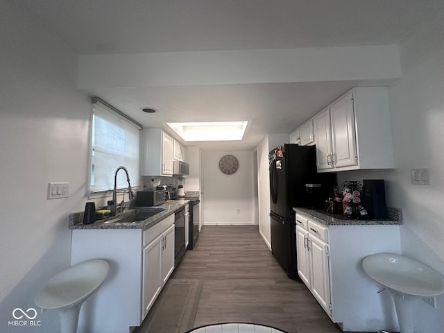 kitchen with white cabinetry, sink, dark stone counters, black appliances, and dark wood-type flooring