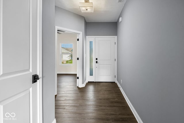 foyer with dark wood finished floors, a textured ceiling, and baseboards