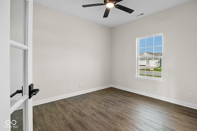 spare room featuring a ceiling fan, dark wood-style flooring, visible vents, and baseboards